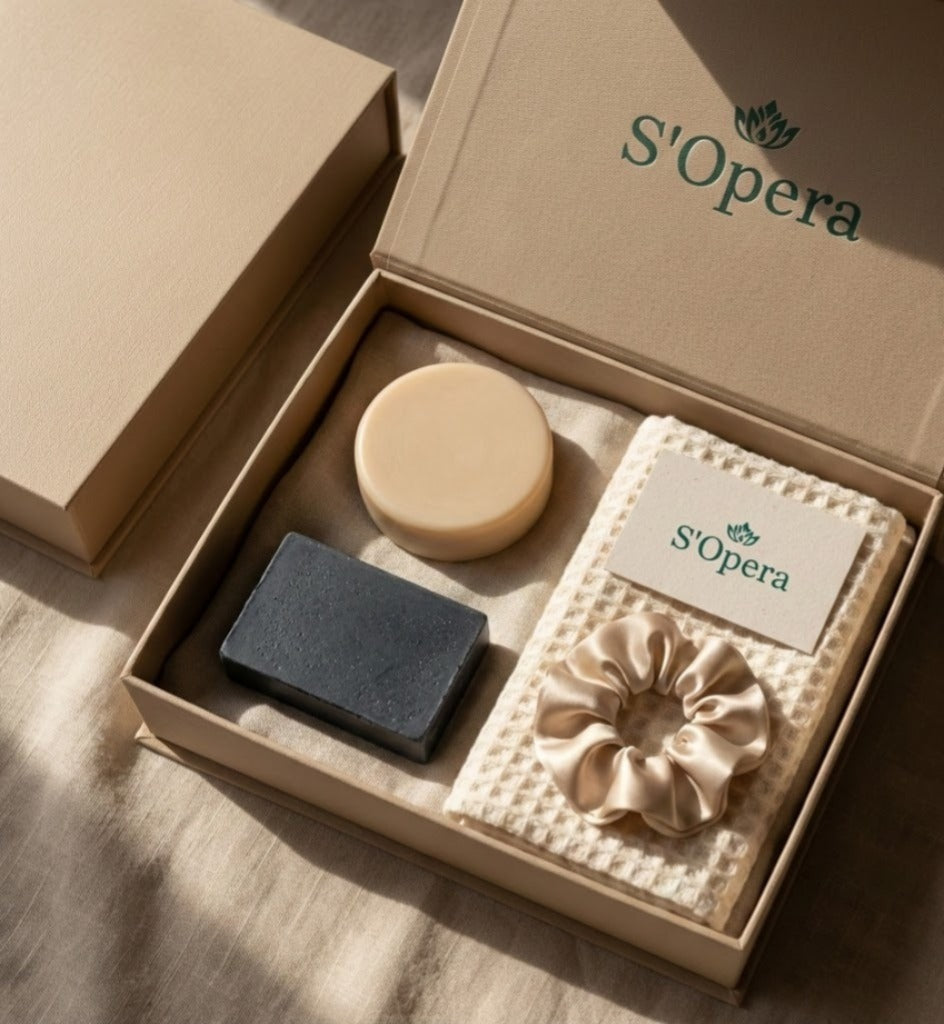 S'Opera beauty product set with scrunchie, bar of soap, and round soap in a box on a wooden surface.
